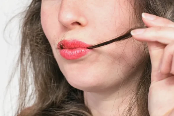 Young beautiful woman with hair strand in red lips. Trichophagia compulsive eating of hair associated with trichotillomania