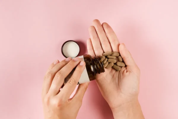 person dropping supplement pills in hand